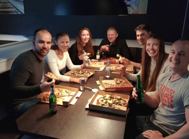 Gruppe isst Pizza und trinkt Bier.