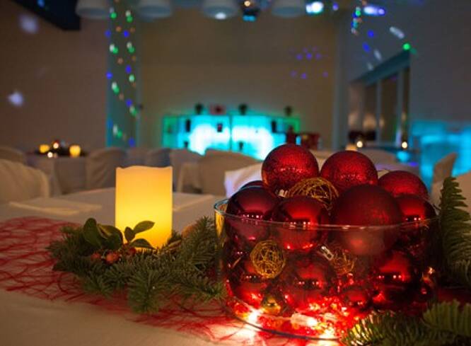 Geschmückter Tisch mit Kerze und Weihnachtsbaumkugeln.