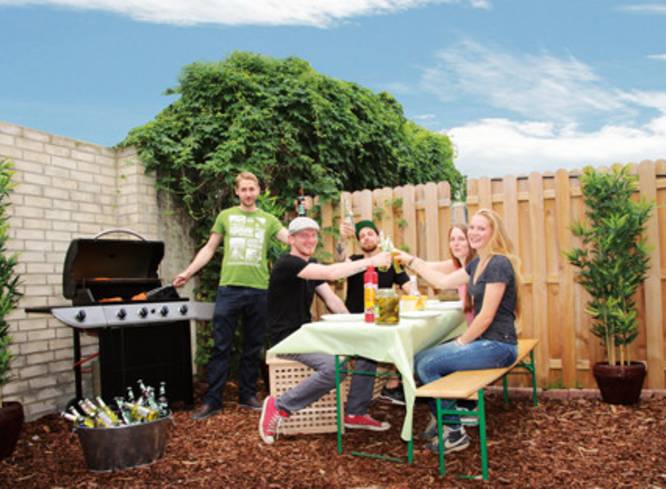 Grillecke mit vier Personen die essen und anstoßen.