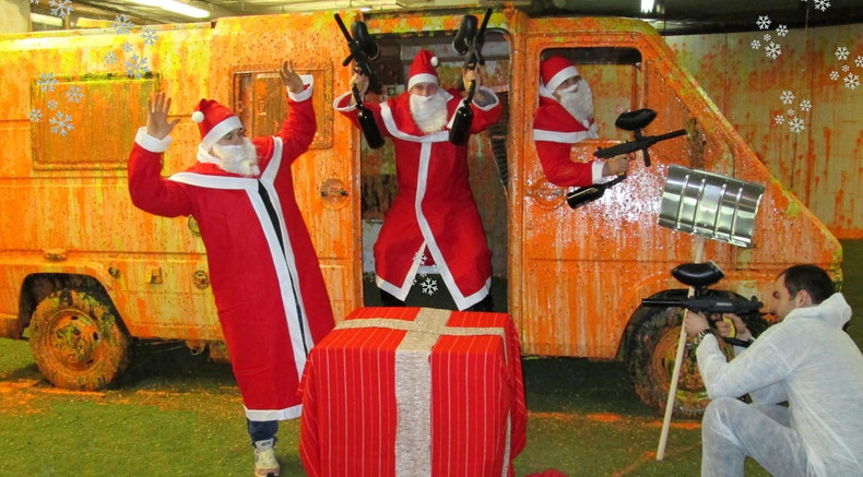 Three santa clauses posing with a paintball marker.